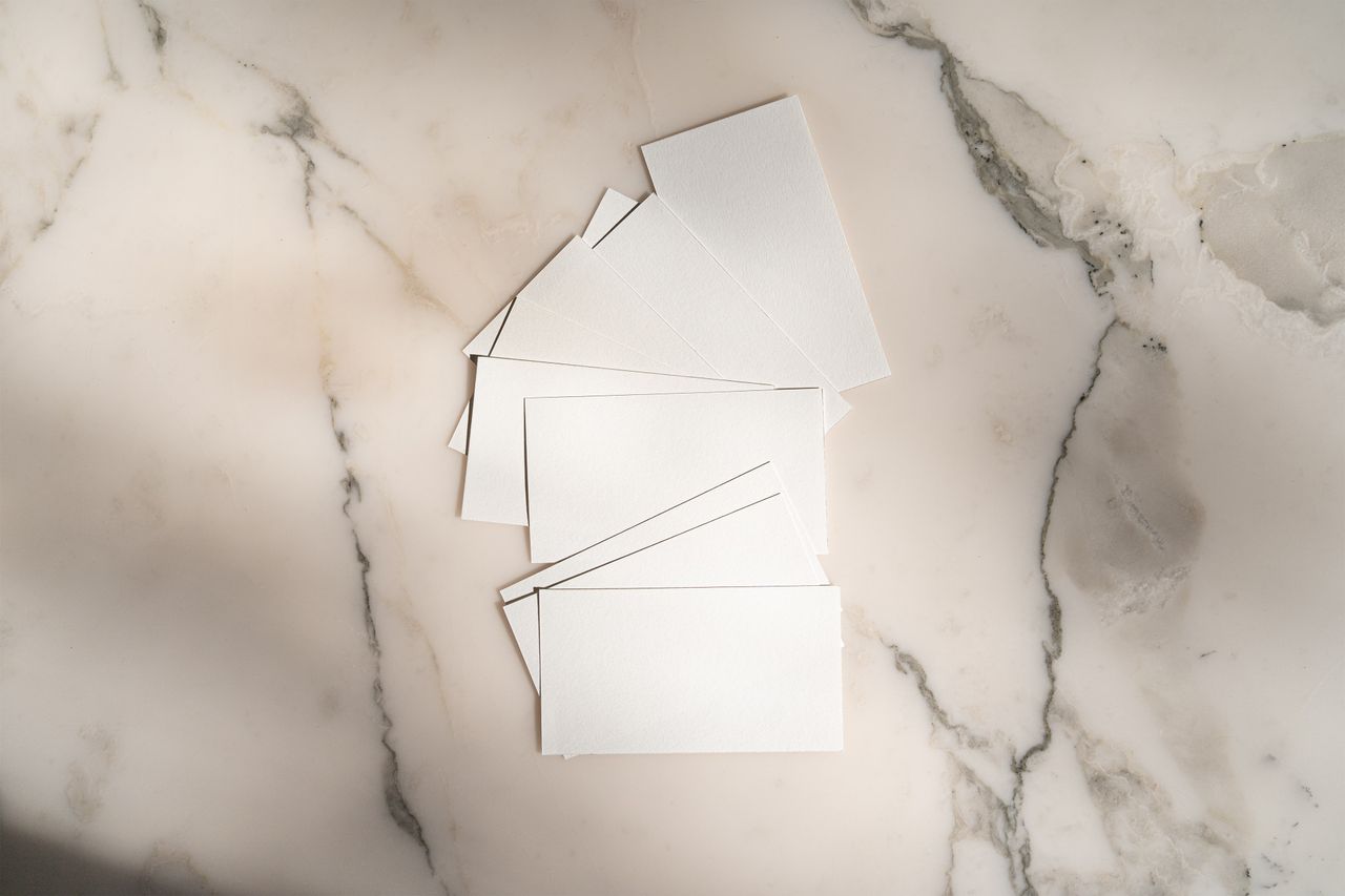 A flat lay of blank white cards arranged on a marble background for creative design use.