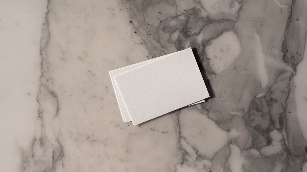 Stack of blank business cards on a marble background, ideal for mockup and design presentations.